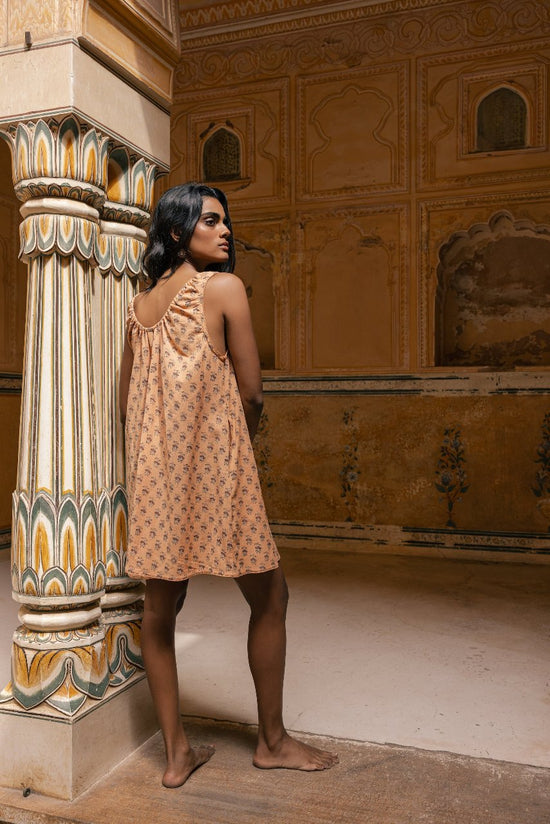 Sundress Mini Peach — studio side profile, sleeveless mini dress with short hemline showing legs, flowing tie-gather neckline, hand block print peach cotton, artisan India | Daughters of India