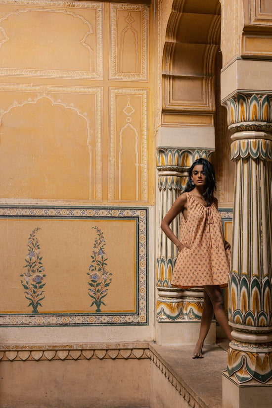 Sundress Mini Peach — beach lifestyle shot, model on sandy shore, short mini sundress hemline, peach floral hand block print cotton, natural setting, artisan Jaipur India | Daughters of India