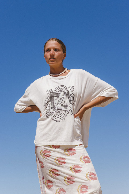 Shanti Tee White — studio close-up upper body front view, white oversized cotton tee with charcoal mandala logo, V-neckline detail, white backdrop | Daughters of India