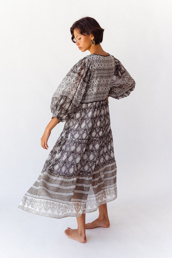 Daughters of India Jasmine Midi Dress in Charcoal — studio back view walking, tiered border hem and balloon sleeves