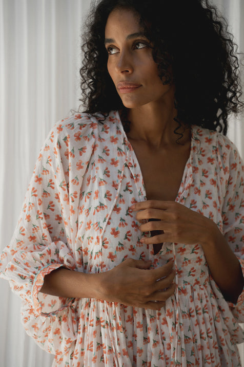 Daughters of India Kyra Maxi Dress in Coral — close-up V-neckline and billowed sleeves by white drape, coral floral print