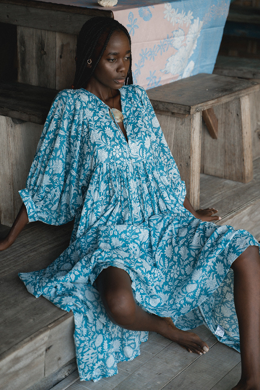 Daughters of India Kyra Midi Dress in Ocean Blue — seated on wooden steps, flowing skirt draped, hand screen print