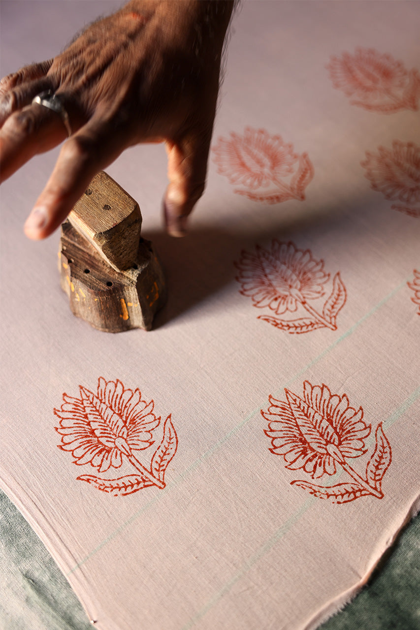 Ria Pants Cherry Blossom — artisan workshop scene, hand-carved wooden printing blocks and cherry blossom printed cotton fabric drying, traditional Sanganer Jaipur India textile craft | Daughters of India