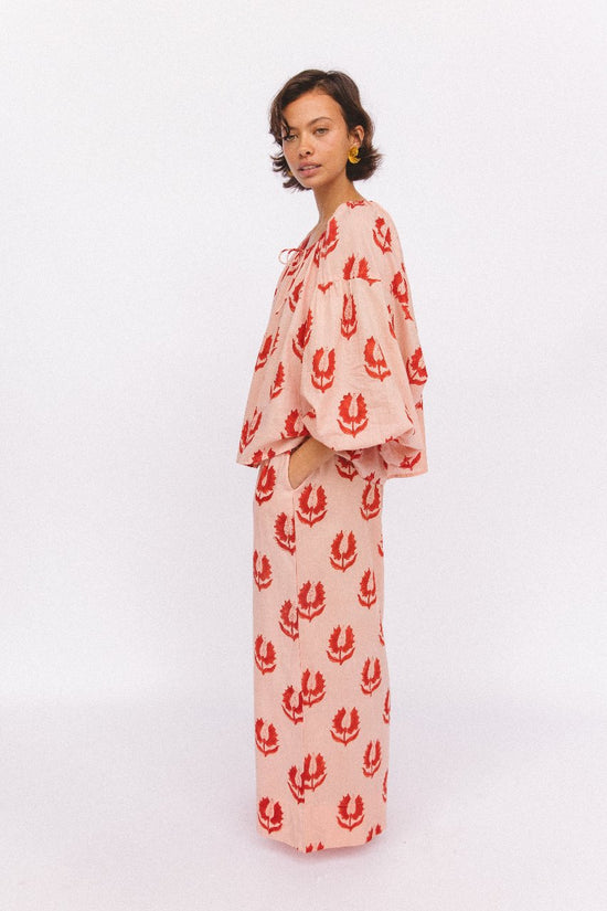 Ria Pants Cherry Blossom — studio back view, model showing rear of cherry blossom hand block print cotton wide-leg pants, pink floral motif on cream, elastic waist detail, artisan Jaipur India | Daughters of India