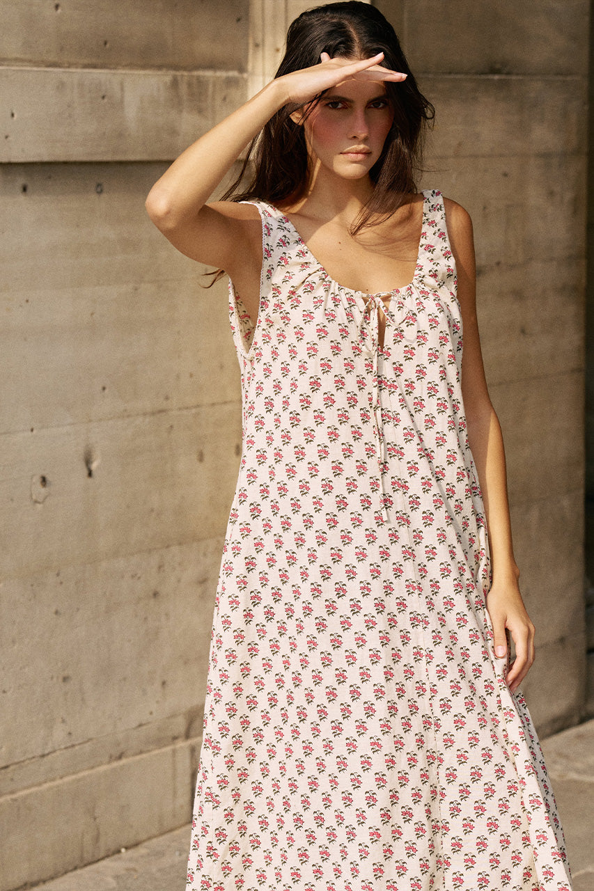 Woman shielding her eyes against a stone wall wearing the Daughters of India Sundress Midi in Peony, showing the full midi length and tie neckline detail
