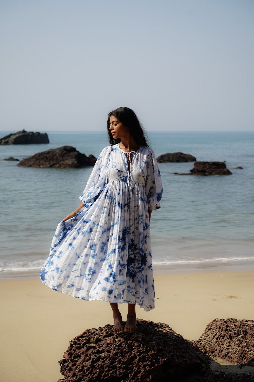 Kyra Midi Dress Deep Sea — full length front view walking on beach, deep sea shibori tie-dye cotton midi dress with flowing tiered skirt, ocean and sand India | Daughters of India